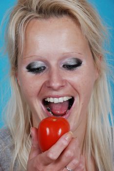 Blond womanl eating a tomato