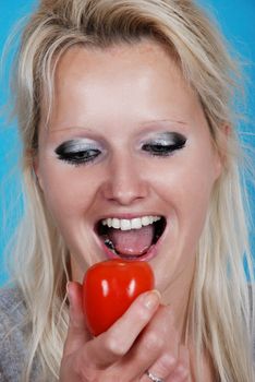 Blond womanl eating a tomato