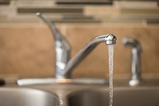 Getting a drink of water from the sink. View has shallow depth of field and is a head on view of a faucet
