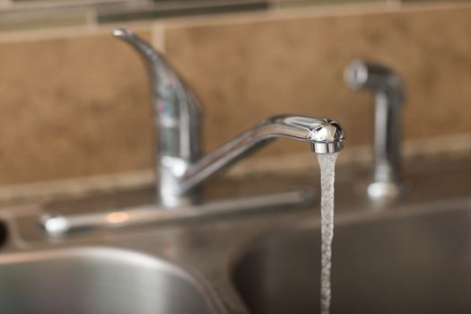 Water coming out of a faucet. View is a 3/4 view with shallow depth of field on the water coming out.
