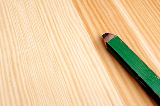 Closeup of green carpentry pencil on wood with copy space