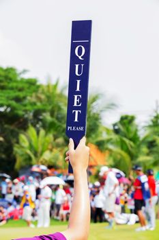 Volunteer holds up a Quiet sign in golf tournament