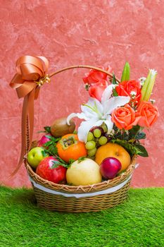 Basket of fruit and flower on green grass and grunge wall