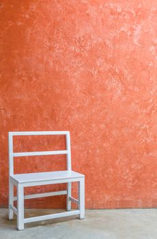 White wood chair and grunge orange color wall