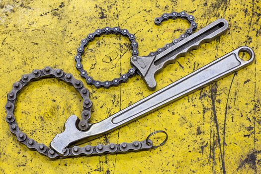 Old and dirty chain wrench on yellow grunge flooe