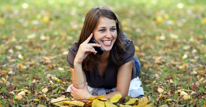 woman calling by phone in autumn park