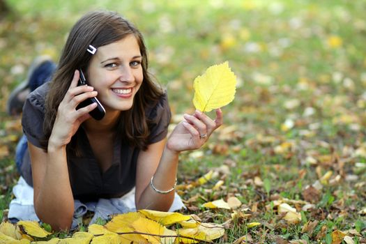 woman calling by phone in autumn park