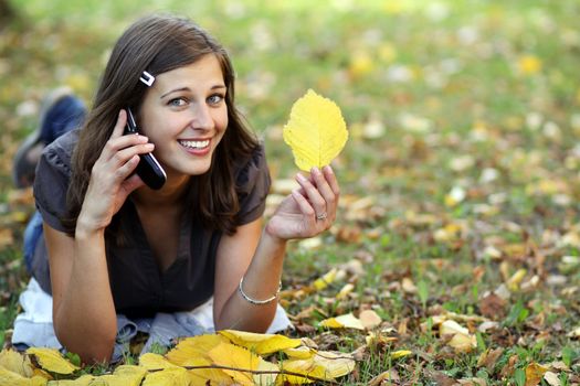 woman calling by phone in autumn park