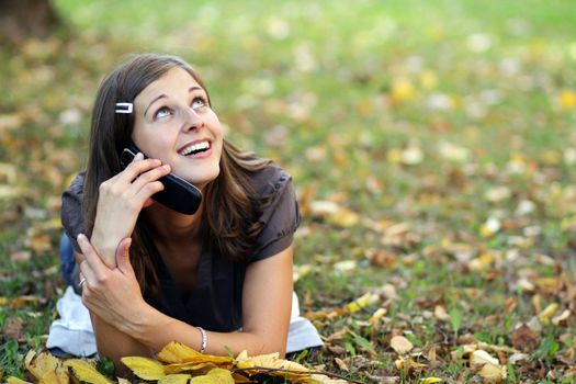 woman calling by phone in autumn park