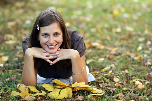 woman lying on a carpet of leaves in autumn park