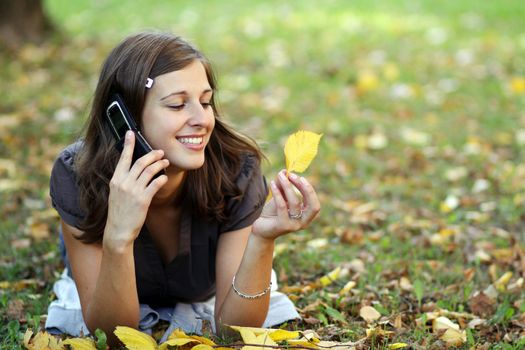 woman calling by phone in autumn park