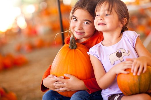 Cute Little Girls Holding Their Pumpkins At A Pumpkin Patch One Fall Day.