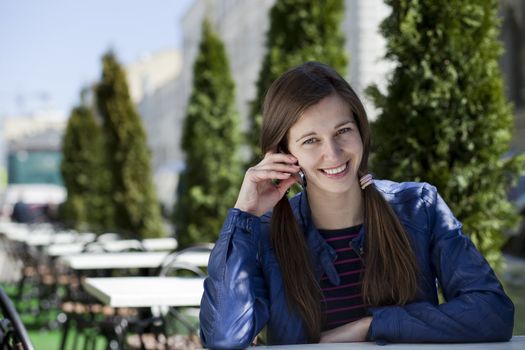 Young happy woman calling by phone on the street
