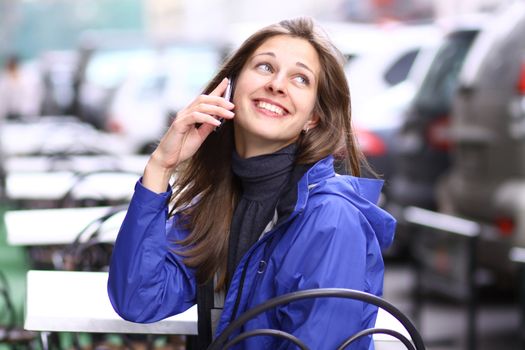 Young happy woman calling by phone on the street