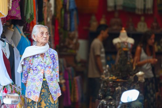 UBUD, BALI, INDONESIA - SEP 19: Old woman stand in the front of souvenir shop on Sep 19, 2012 in Ubud, Bali, Indonesia. Female life expectancy at birth in the county is 74 years. 