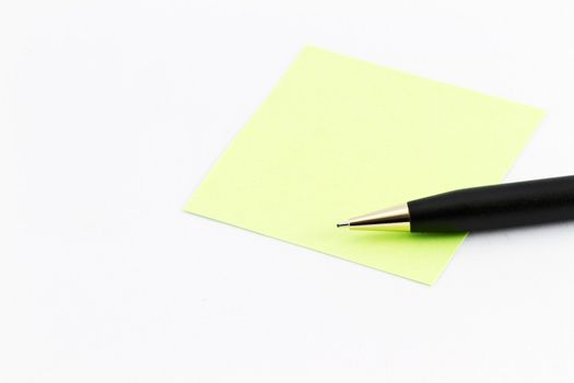 Light green note with clear copy space placed with black pen on white background; nobody; open space on paper for message or list;