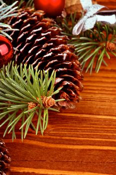 Arrangement of Spruce Branch, Fir Cones and Red Baubles closeup on Wooden background