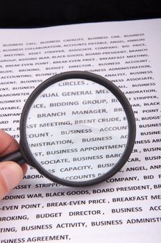 An image of magnify glass over paper with written business slang