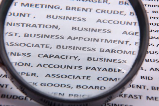 An image of magnify glass over paper with written business slang