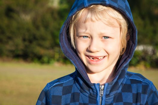 A close-up portrait of a cute happy smiling boy with missing front teeth.