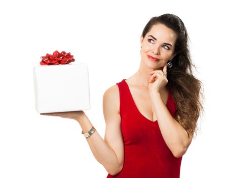 A beautiful woman holding up a beautiful gift and looks thoughtful. Isolated on white.