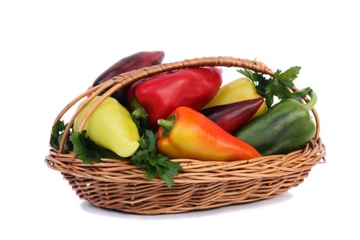 Wicker basket filled with ripe red, yellow, green peppers. Presented on a white background.