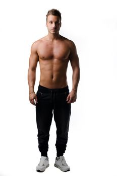 Full body shot of muscular young man standing and looking in camera, shirtless