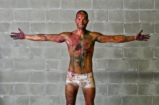 Handsome young man with skin all painted with colors, arms spread open
