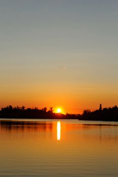 Colorful sunset over tranquil water surface.