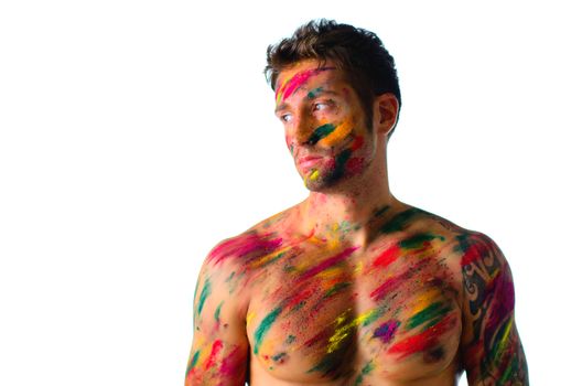 Attractive and athletic shirtless young man, skin painted all over with Holi colors, isolated on white