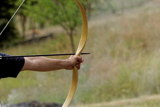 archery man shooting arrow with bow in the nature