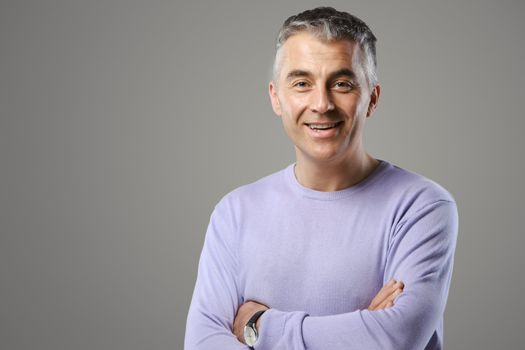 Portrait of casual man standing  and smiling on grey background