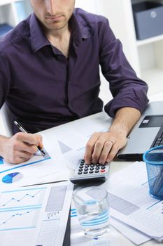 Business man checking financial data on calculator.
