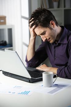 Stressful young man working on laptop