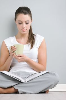 Portrait of young woman with book holding a cup of coffee or tea