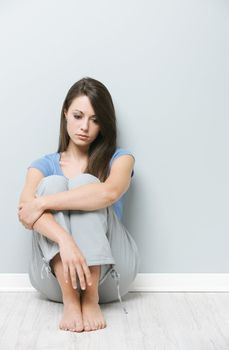 Young sad woman sitting on floor at home 