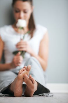 Young woman sitting on the floor with a rose in hand