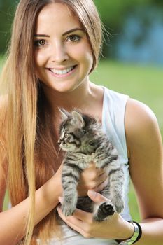 Smiling young woman playing outdoors with her kitty
