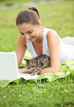 Beautiful girl with her kitty and laptop outdoors