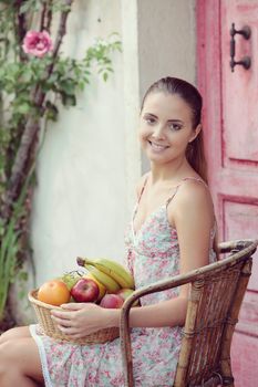 Cheerful young woman with a basket of fresh fruit