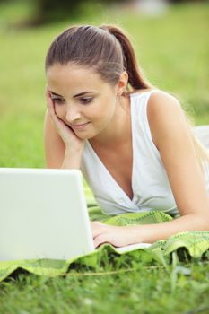 Cheerful girl working in laptop outdoors in a sunny day