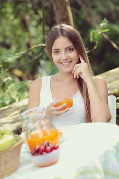 Young woman relaxes in the garden drinking a orange juice