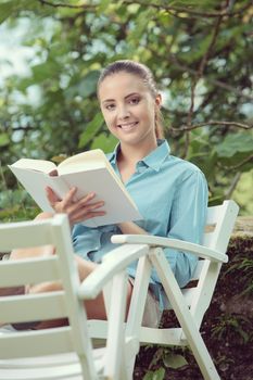 Beautiful girl reading a book outdoors enjoying a summer day