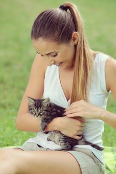 Beautiful young woman playing outdoors with her kitty