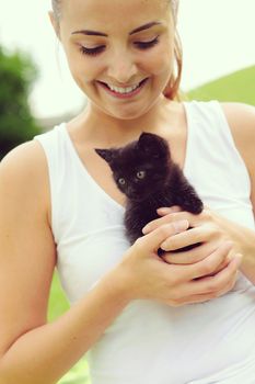 Beautiful young woman playing outdoors with her kitty