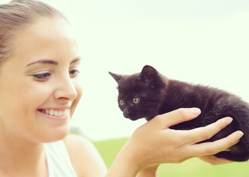 Beautiful young woman playing outdoors with her kitty