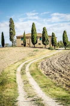 landscape in tuscany, italy with house, fields, cypresses and blue sky