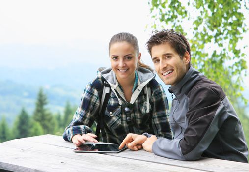 Smiling couple using tablet on the mountain