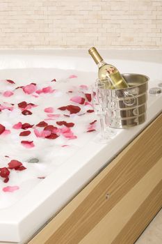 A relaxing bath with rose petals ,wine and glassess