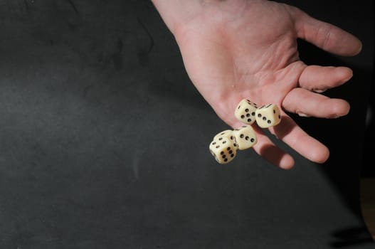 One Left Male Hand Playing Dice on a Black Background